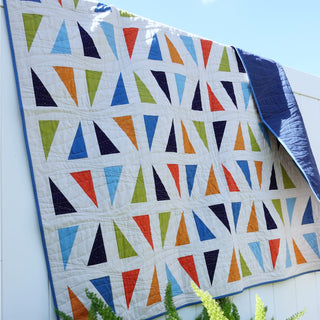 Jubilant Quilt Pattern (Download) by Homemade Emily Jane featuring colorful geometric triangles on a modern white quilt with bold negative space