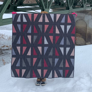 Jubilant Quilt Pattern (Download) by Homemade Emily Jane featuring a modern geometric quilt with bold pink gray and white triangles on a charcoal background
