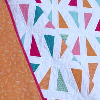 Jubilant Quilt Pattern (Download) by Homemade Emily Jane featuring colorful triangle blocks and playful negative space in a modern quilt design