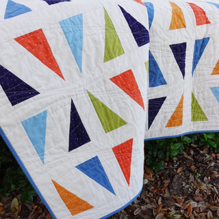 Jubilant Quilt Pattern (Download) by Homemade Emily Jane featuring a modern geometric quilt with colorful triangles and white negative space.