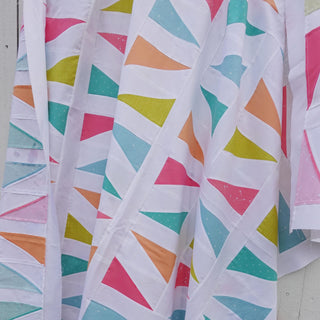 Jubilant Quilt Pattern (Download) by Homemade Emily Jane featuring colorful triangle blocks and bold white negative space in a modern quilt design