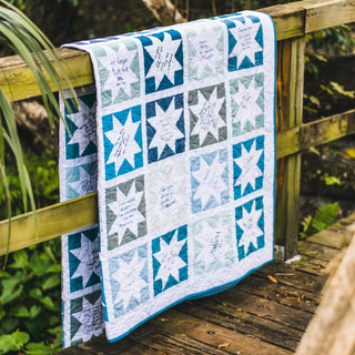 Keepsake Quilt Pattern (Download) by Homemade Emily Jane, featuring a blue, white, and gray star block quilt draped over a wooden bridge railing