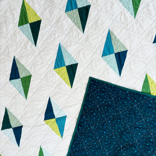 Luminary Quilt Pattern (Download) by Homemade Emily Jane, a modern geometric quilt with colorful angular shapes on white and a dark teal quilted section