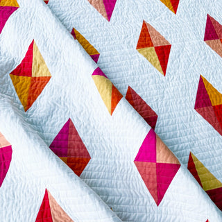 Luminary Quilt Pattern (Download) by Homemade Emily Jane featuring a modern geometric quilt with colorful diamond shapes on a soft blue background