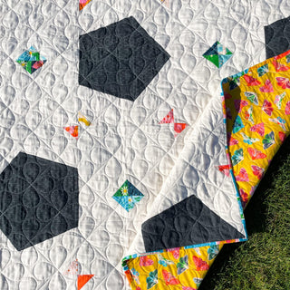 Soccer Party Quilt Pattern (Download) by Jessica Steele Design showing a modern soccer inspired quilt with black geometric balls and colorful fabric accents
